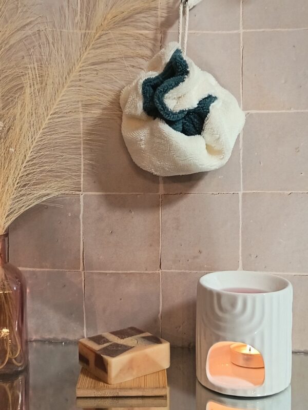 Fleur de douche écologique en bambou, mélange de bleu indigo et de crème, présentée dans un décor de bien-être naturel.