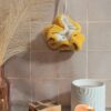 Fleur de douche bicolore jaune moutarde et crème en fibre de bambou, idéale pour une routine beauté zéro déchet.