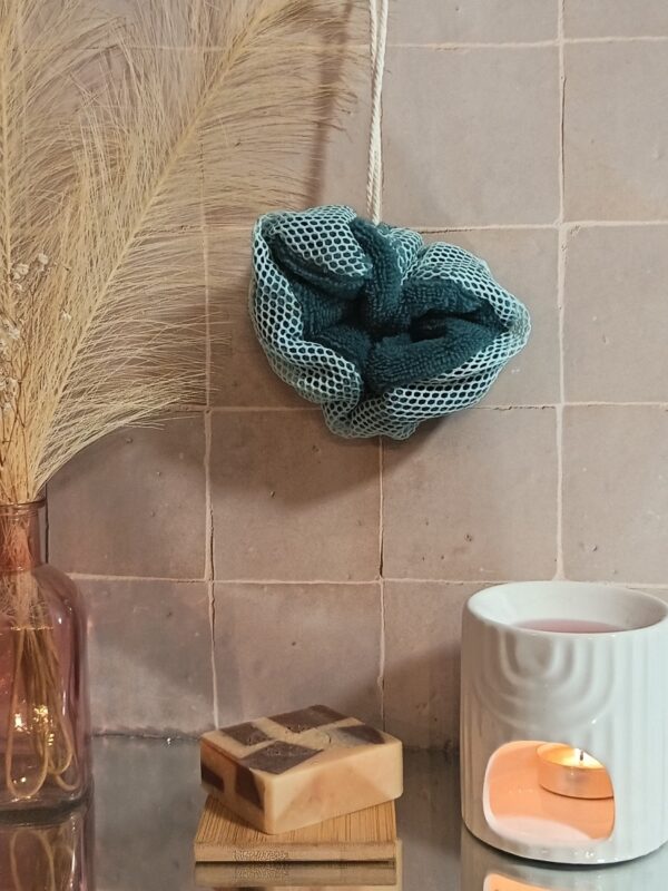 Fleur de douche écoresponsable aux teintes vert canard et vert d'eau, présentée dans un décor de salle de bain naturel et chaleureux.