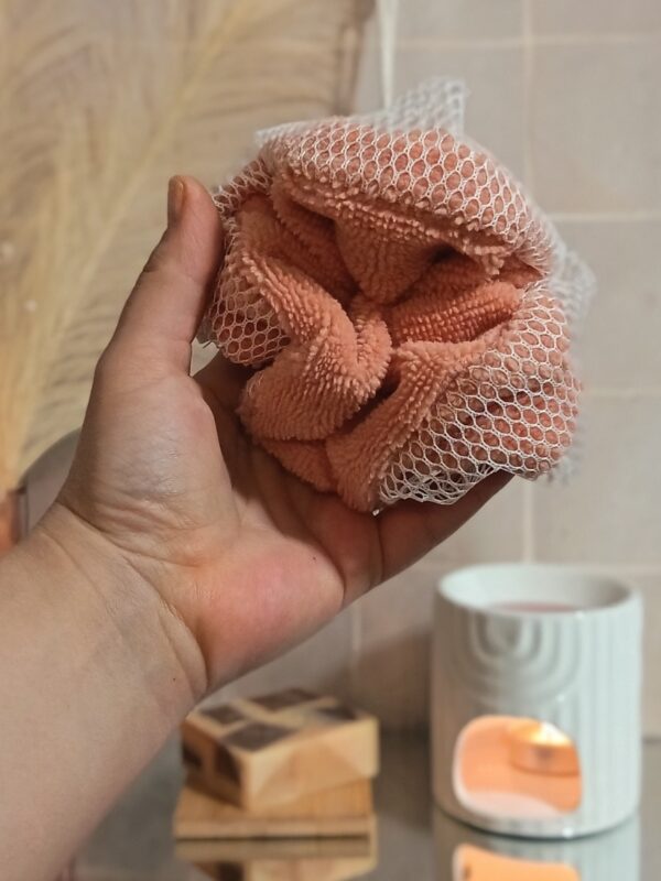 Main tenant une fleur de douche lavable pêche et blanche pour illustrer sa taille généreuse et sa prise en main ergonomique.