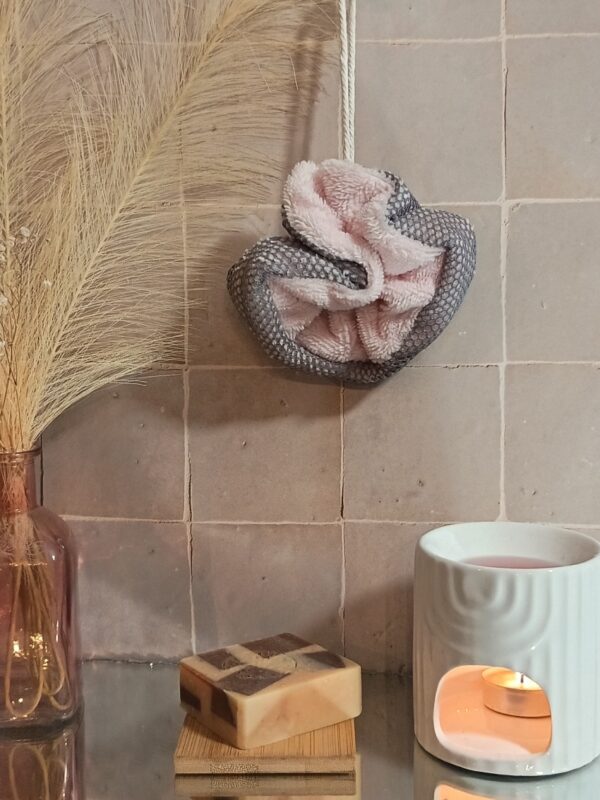 Fleur de douche en tissu rose tendre et filet gris anthracite, mise en scène avec des éléments de décoration bohème chic.