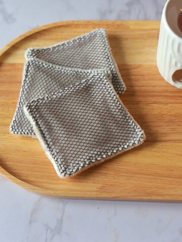 Lot de lingettes lavables exfoliantes avec une face en filet de coton gris pour un gommage doux du visage et un verso en éponge de bambou crème.