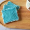 Lingettes démaquillantes gommantes avec filet texturé bleu turquoise, idéales pour un soin du visage zéro déchet et tonifiant.