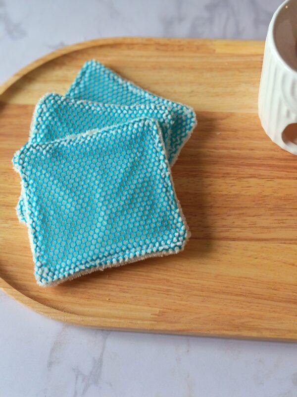 Lingettes démaquillantes gommantes avec filet texturé bleu turquoise, idéales pour un soin du visage zéro déchet et tonifiant.