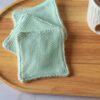 Lingettes lavables bifaces avec filet exfoliant vert d'eau et éponge de bambou ultra-douce pour nettoyer et exfolier la peau en douceur.