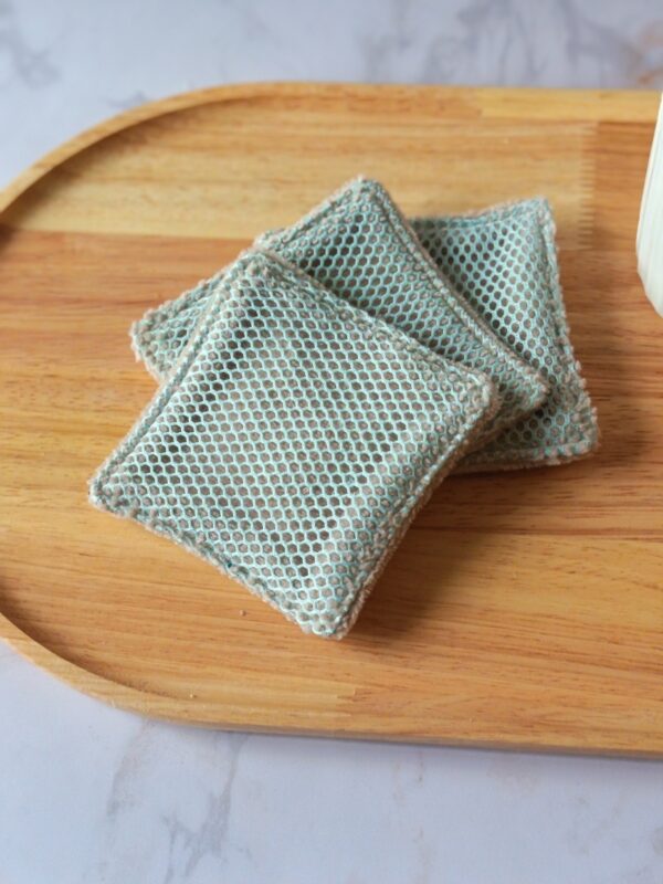 Duo de textures pour ces lingettes lavables : un filet exfoliant vert d'eau monté sur une base en tissu éponge coloris taupe.