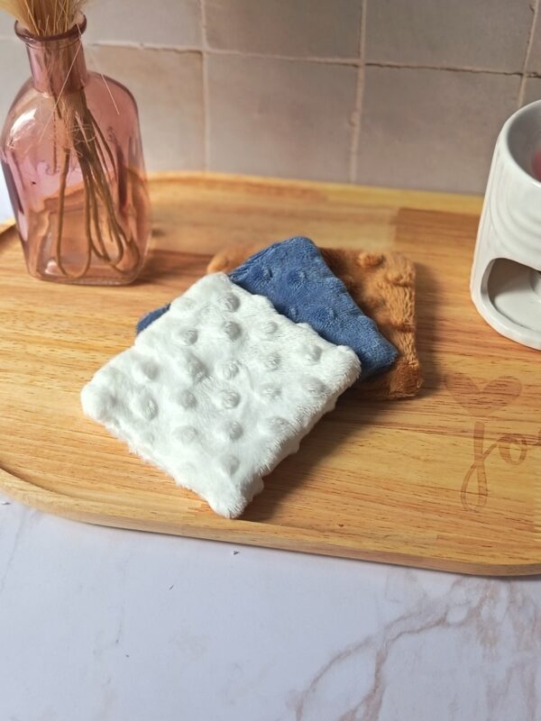 Trio de lingettes démaquillantes lavables collection Douceur Ocre Bleuté sur plateau en bois.