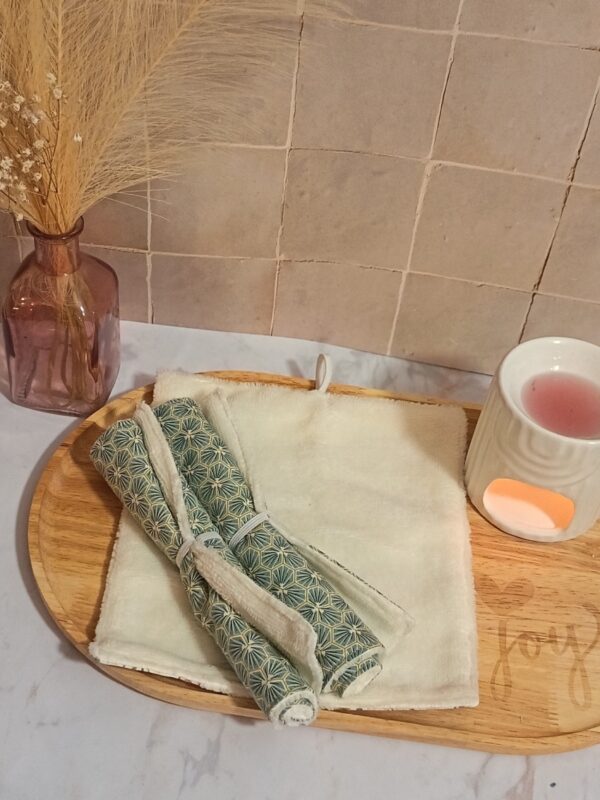 Serviette de toilette écologique en bambou coloris crème présentée à plat et roulée, avec un tissu à motif géométrique d'hexagones "art déco" dans les tons vert sapin et doré.