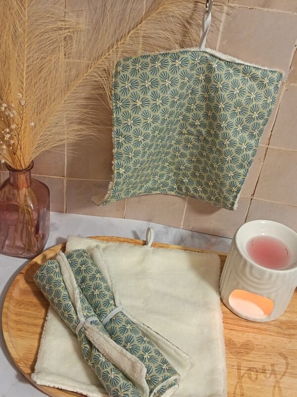 Carré de soin visage en bambou suspendu avec un motif géométrique hexagone vert et or. En dessous, la serviette est présentée dépliée pour montrer sa face éponge crème ultra-douce.