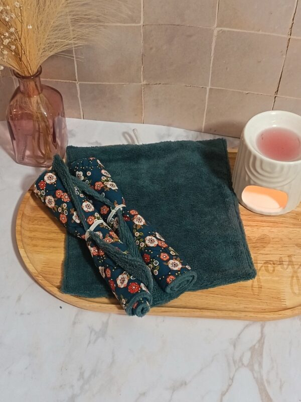 Duo de serviettes multi-usages enroulées avec le motif "Okaido" (fleurs japonaises rouges et blanches sur fond bleu), posées sur une serviette en bambou indigo dépliée.