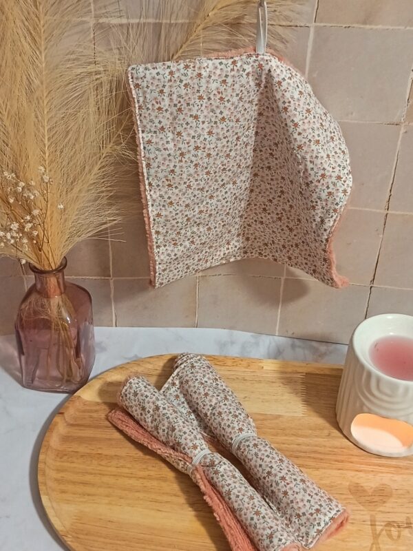 Serviette de toilette suspendue montrant un tissu fleuri délicat et une face absorbante en bambou de couleur pêche.