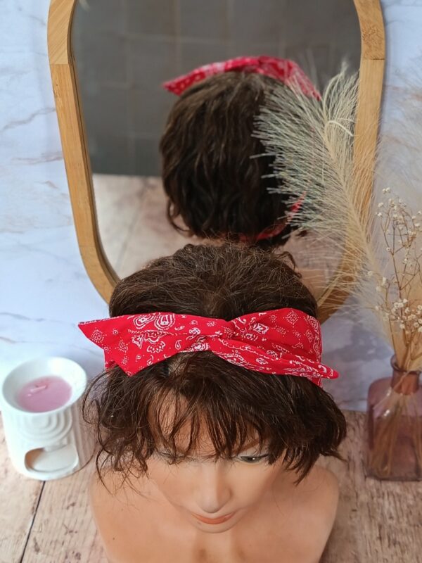 Bandeau pour cheveux avec fil de fer intégré, motif bandana rouge et blanc. Présenté sur une tête de mannequin, noué sur le dessus, il maintient les cheveux courts avec une touche rétro et élégante.