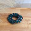 Chouchou bleu pétrole avec plein de petit cœur coloré en coton posé pour accessoiriser une tenue.