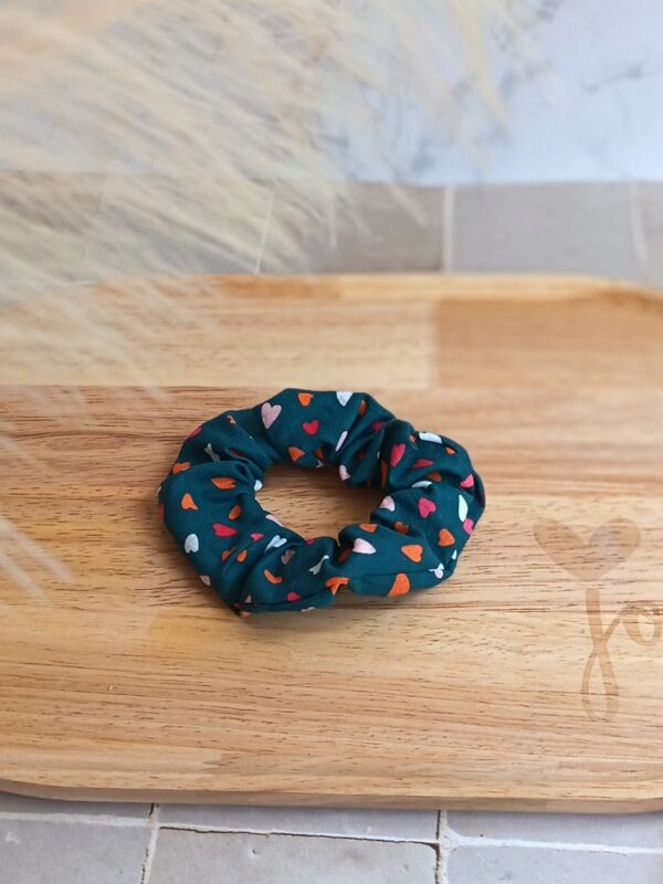 Chouchou bleu pétrole avec plein de petit cœur coloré en coton posé pour accessoiriser une tenue.
