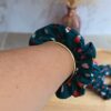 Chouchou bleu pétrole avec plein de petit cœur coloré en coton porté au poignet pour accessoiriser une tenue.