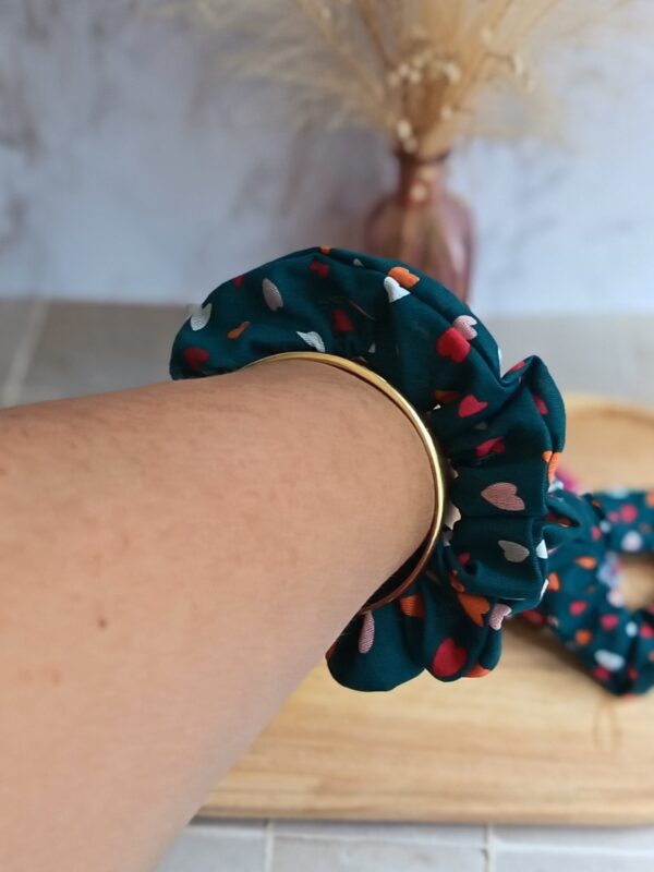 Chouchou bleu pétrole avec plein de petit cœur coloré en coton porté au poignet pour accessoiriser une tenue.