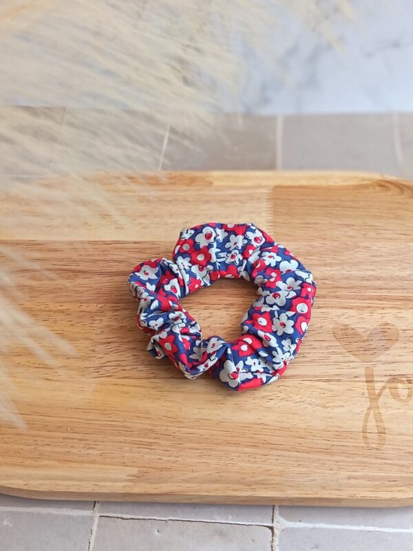 Chouchou bleu avec petite fleur rose et blanche en coton posé pour accessoiriser une tenue.