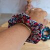 Chouchou bleu avec petite fleur rose et blanche en coton porté au poignet pour accessoiriser une tenue.