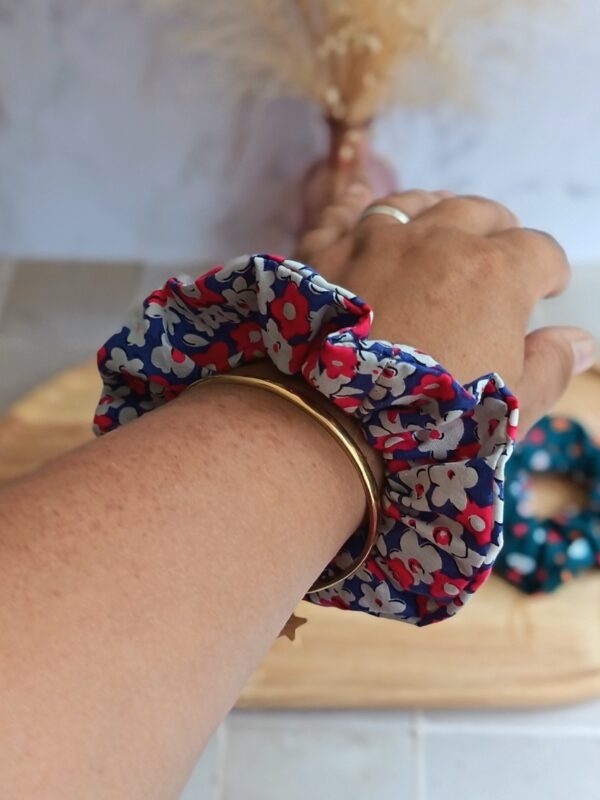 Chouchou bleu avec petite fleur rose et blanche en coton porté au poignet pour accessoiriser une tenue.