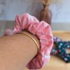 Chouchou rose avec forme géométrique blanche et blanche en coton porté au poignet pour accessoiriser une tenue.