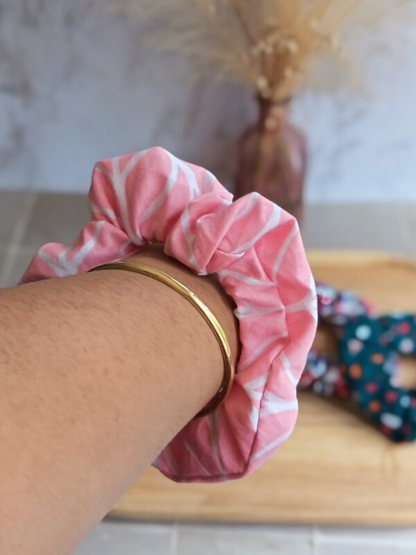 Chouchou rose avec forme géométrique blanche et blanche en coton porté au poignet pour accessoiriser une tenue.