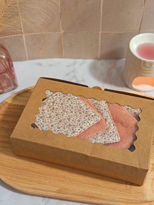 Packaging éco-responsable du coffret bien-être : boîte en carton kraft avec fenêtre découpée laissant apparaître les accessoires en bambou et coton fleuri.