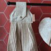 Zoom sur la texture absorbante du nid d'abeille lin et l'imprimé fleuri de l'essuie-main suspendu.