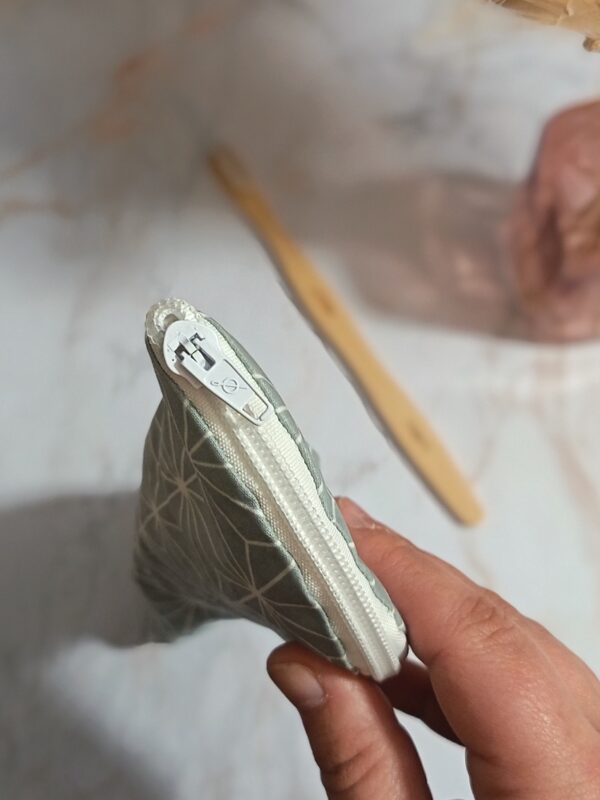 Gros plan sur la fermeture éclair blanche et robuste d'un étui à brosse à dents artisanal en coton enduit.