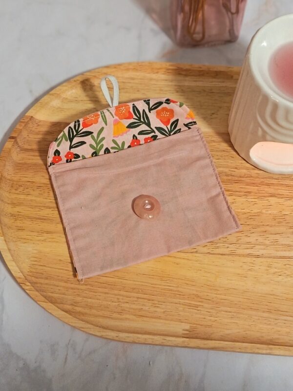 Étui à savon imperméable modèle Martine, de couleur rose poudré. Le rabat ouvert montre une doublure au motif floral printanier avec de petites fleurs oranges, roses et jaunes sur fond clair.