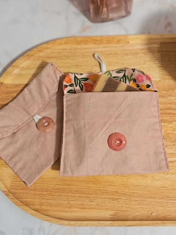 Présentation de deux étuis roses : l'un fermé montrant son bouton rose brillant, l'autre ouvert contenant un savon artisanal, laissant apparaître la doublure fleurie.