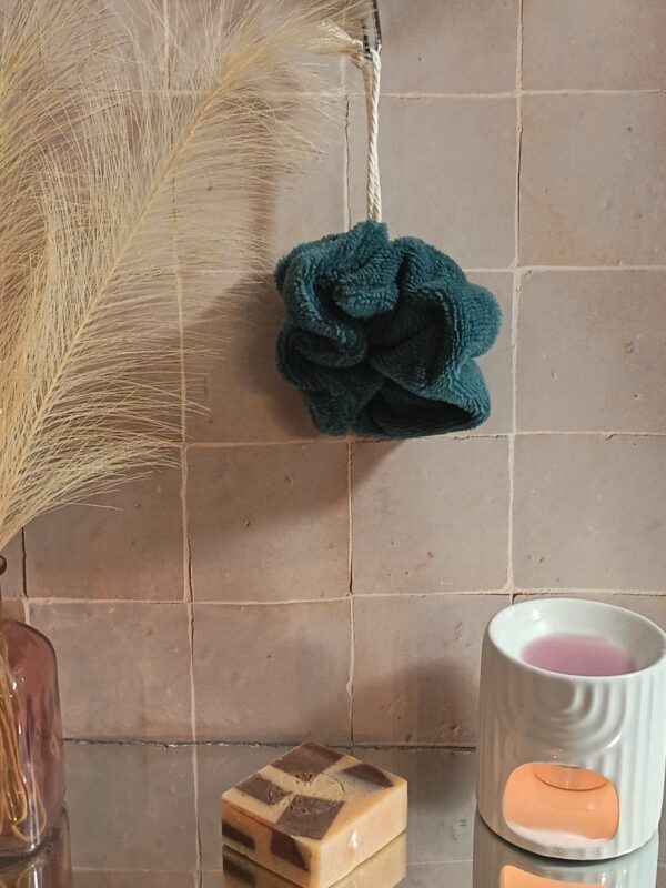 Fleur de bain éco-responsable coloris bleu indigo profond en tissu éponge de bambou, suspendue à une cordelette blanche.