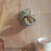 Fleur de douche lavable combinant un tissu éponge taupe et un filet de maintien vert d'eau, ambiance spa.