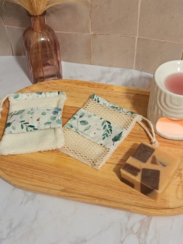 Ensemble de deux gants sauve-savon artisanaux avec motifs eucalyptus et touches dorées, présentés sur un plateau en bois avec un savon solide pour un rituel bain zéro déchet.