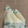 Plan rapproché sur le système de fermeture par cordon d'un gant sauve-savon, illustrant comment le savon est maintenu en sécurité à l'intérieur de la pochette en bambou.