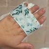 Vue détaillée de la lanière de maintien d'un gant sauve-savon passée sur le dos de la main, assurant une prise en main stable et confortable pendant la douche.