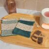 Duo de pochettes à savon avec un tissu fleuri délicat "Mini Pio" aux teintes rose et kaki, montées sur une éponge de bambou bleu indigo profonde pour un contraste élégant.