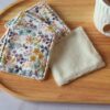 Carrés démaquillants lavables faits main avec un tissu floral aux tons ocre, violet et bleu sur fond blanc.