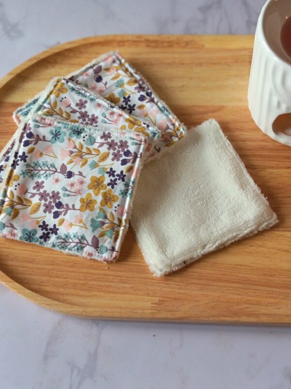 Carrés démaquillants lavables faits main avec un tissu floral aux tons ocre, violet et bleu sur fond blanc.