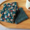 Lingettes démaquillantes lavables avec tissu japonais bleu canard à fleurs rouges et blanches, face absorbante en éponge gris foncé.