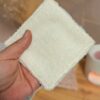 Gros plan sur la face en éponge de bambou blanche d'une lingette lavable, montrant la texture moelleuse et absorbante adaptée aux peaux sensibles.