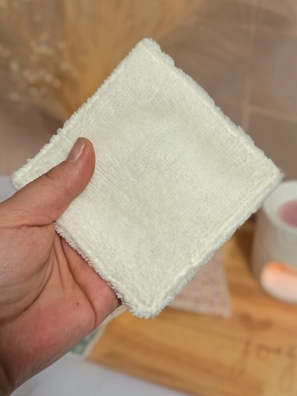 Gros plan sur la face en éponge de bambou blanche d'une lingette lavable, montrant la texture moelleuse et absorbante adaptée aux peaux sensibles.