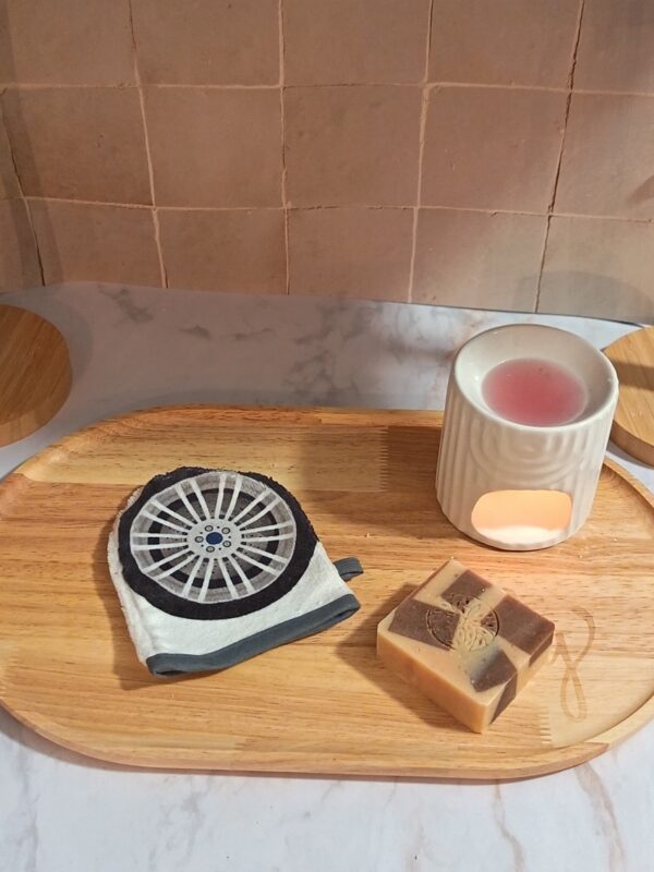 Gant de toilette individuel blanc avec un imprimé original représentant une jante de voiture grise et noire, posé à côté d'un savon artisanal.