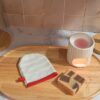Lingette de toilette en forme de gant avec un motif discret de rayures blanches et une finition avec un biais rouge vif.