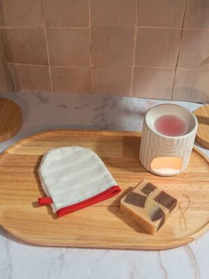 Lingette de toilette en forme de gant avec un motif discret de rayures blanches et une finition avec un biais rouge vif.