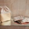 Panier à lingettes lavables refermé grâce à son cordon de serrage, se transformant en pochon de transport pratique pour les déplacements zéro déchet.
