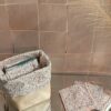Panier de salle de bain ouvert présentant un lot de lingettes démaquillantes réutilisables, avec un revers en tissu Liberty à petites fleurs et une base robuste en simili-cuir.