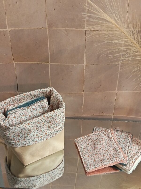 Panier de salle de bain ouvert présentant un lot de lingettes démaquillantes réutilisables, avec un revers en tissu Liberty à petites fleurs et une base robuste en simili-cuir.