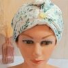 Serviette à cheveux turban en éponge de bambou blanche avec tissu extérieur aux motifs de feuilles d'eucalyptus vertes et bouton doré.
