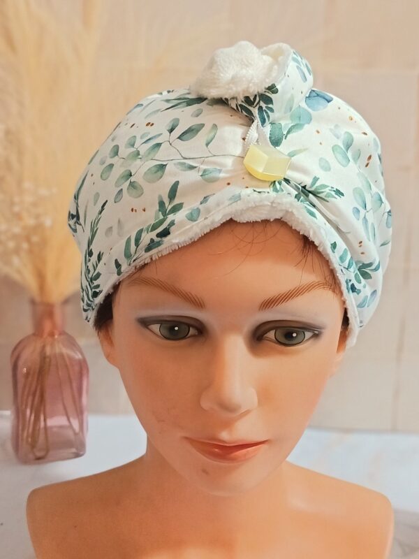 Serviette à cheveux turban en éponge de bambou blanche avec tissu extérieur aux motifs de feuilles d'eucalyptus vertes et bouton doré.