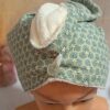 Turban serviette à cheveux en éponge de bambou blanche et tissu à motifs géométriques d'éventails verts et dorés avec bouton transparent.